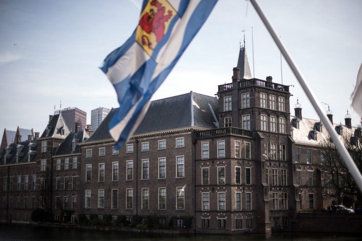 Dutch parliament building with flags and people, symbolizing political discussions, governance, and legislative activities