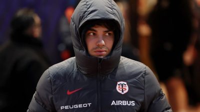 GettyImages 2255707985 showing a bustling city street with diverse pedestrians and modern buildings under a clear blue sky