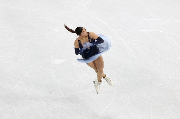 Business professionals discussing strategies in a modern office setting with digital graphs on a large screen in the backg...
