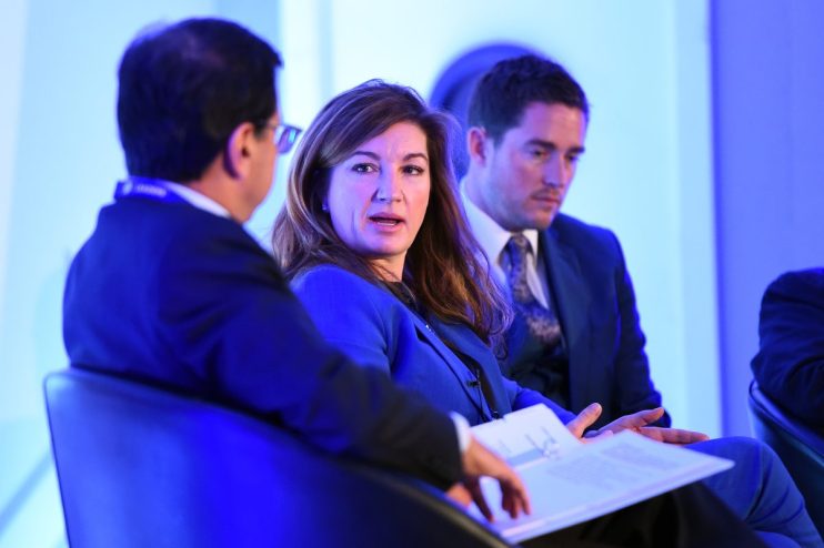 Karren Brady speaking at a business conference, dressed in professional attire, engaging with an audience on stage