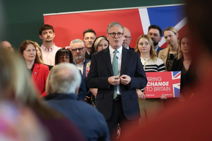 Labour Party leaders discussing policy strategies at a conference, with banners and attendees in the background