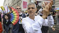 Sadiq Khan proudly participating in a vibrant Pride parade, surrounded by colorful flags and joyful attendees in London.
