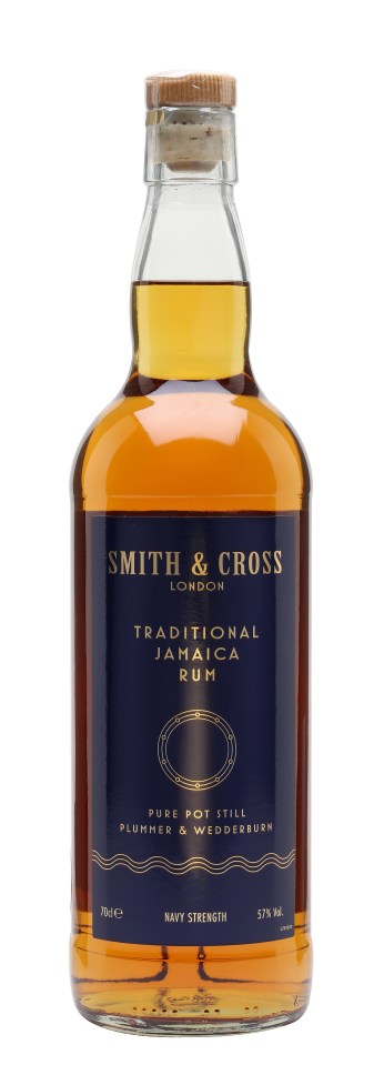 Smith Cross Rum bottle on a wooden table with a nautical-themed label, surrounded by tropical fruits and cocktail ingredients