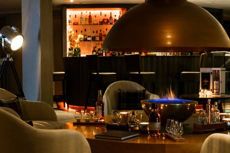 Cozy living room with a modern fireplace at The Snug, featuring elegant decor and warm ambient lighting.