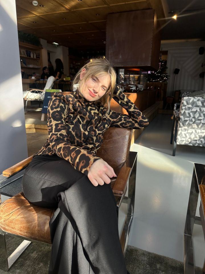 Leopard resting on tree branch in natural habitat, showcasing distinctive spotted fur pattern against lush greenery backgr...