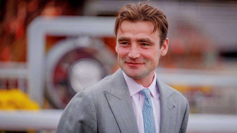 Breaking news event scene with journalists gathered, cameras flashing, and a prominent cityscape backdrop in daylight