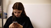 Teenager looking at smartphone with social media ban notification, emphasizing digital restrictions and online safety conc...