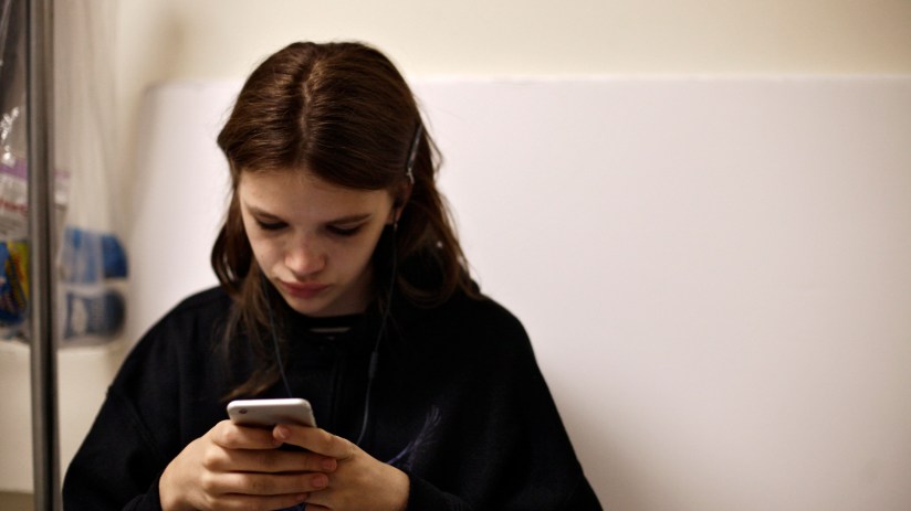 Teenager looking at smartphone with social media ban notification, emphasizing digital restrictions and online safety conc...
