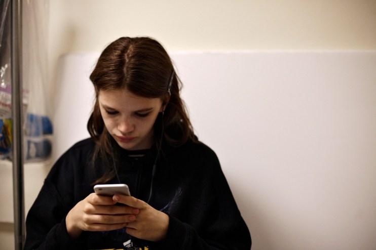 Teenager looking at smartphone with social media ban notification, emphasizing digital restrictions and online safety conc...