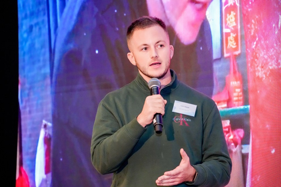 Harry Jaggard shares insights on his Macao experience at a conference podium, capturing audience engagement and interest.