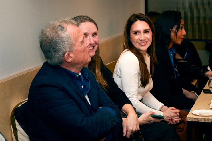Professional women in business attire discussing a project at a conference table, highlighting diversity and collaboration