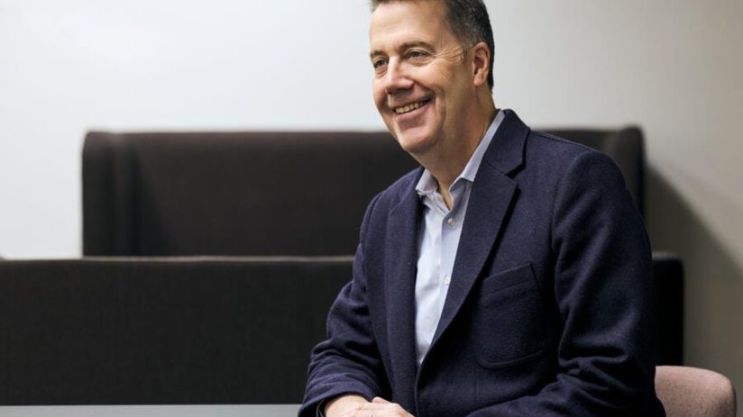 Business professional AB in formal attire, smiling confidently in headshot, suitable for corporate or news media profile.