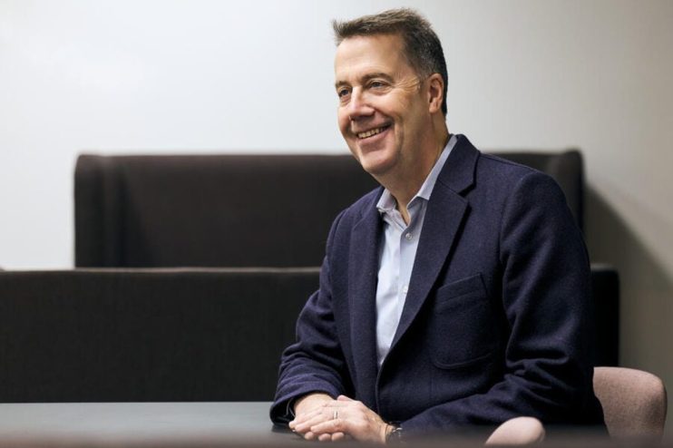 Business professional AB in formal attire, smiling confidently in headshot, suitable for corporate or news media profile.