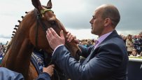 Adrian Keatley, horse racing trainer, standing in a stable with horses, showcasing his expertise in the equestrian industry.