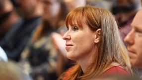 Angela Rayner speaking at a podium during a conference, addressing audience with a serious expression and gesturing with h...