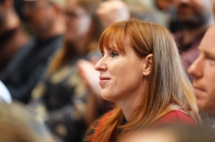 Angela Rayner speaking at a podium during a conference, addressing audience with a serious expression and gesturing with h...