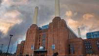 Battersea Power Station in London with iconic chimneys, urban redevelopment, and cloudy sky backdrop