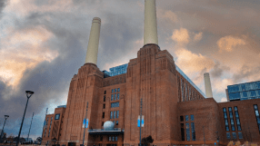 Battersea Power Station in London with iconic chimneys, urban redevelopment, and cloudy sky backdrop