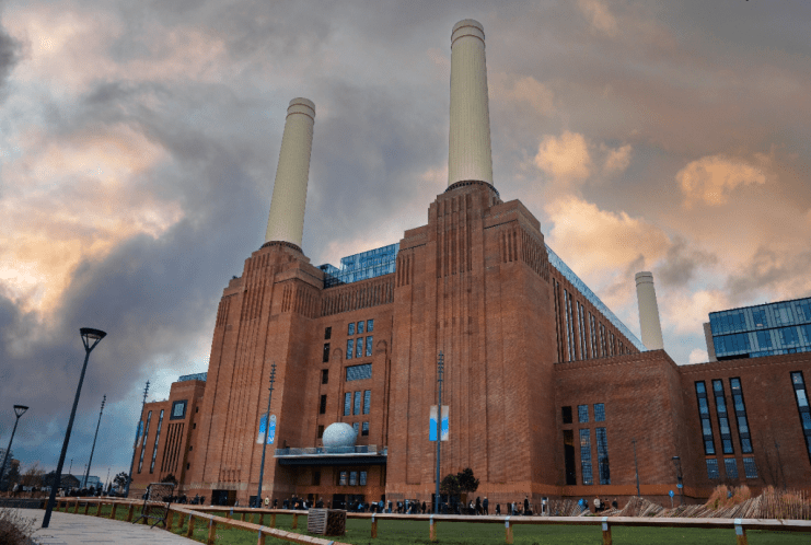 Battersea Power Station in London with iconic chimneys, urban redevelopment, and cloudy sky backdrop