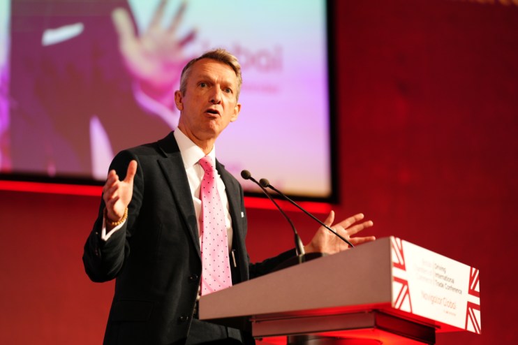 Andy Haldane, British Chambers of Commerce president, addressing a business conference, wearing a suit and tie.