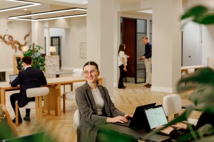 Modern coworking space with diverse professionals collaborating at desks, fostering creativity and productivity in a share...