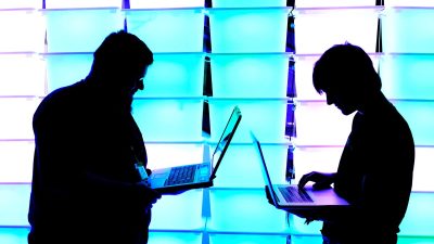 Programmer typing on a laptop with code editor open, showcasing lines of computer code in a bright, modern office setting