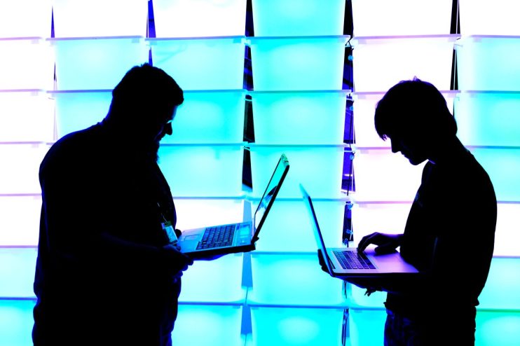Programmer typing on a laptop with code editor open, showcasing lines of computer code in a bright, modern office setting