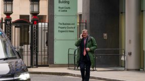Crispin Odey attending a high-profile business event, wearing a formal suit, surrounded by investors and financial experts.