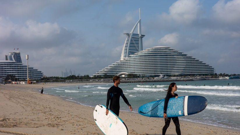 Surfers riding waves in Dubais coastline, highlighting the citys appeal for tax exiles seeking vibrant lifestyle opportuni...