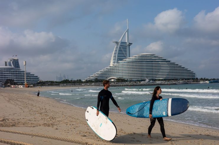 Surfers riding waves in Dubais coastline, highlighting the citys appeal for tax exiles seeking vibrant lifestyle opportuni...