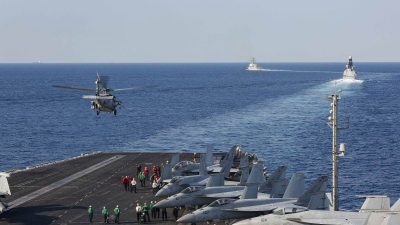 View of the strategic Strait of Hormuz with passing cargo ships under a clear sky, highlighting global trade routes.