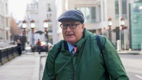 Crispin Odey standing in a formal suit at a business event, engaging in conversation with attendees, showcasing business n...