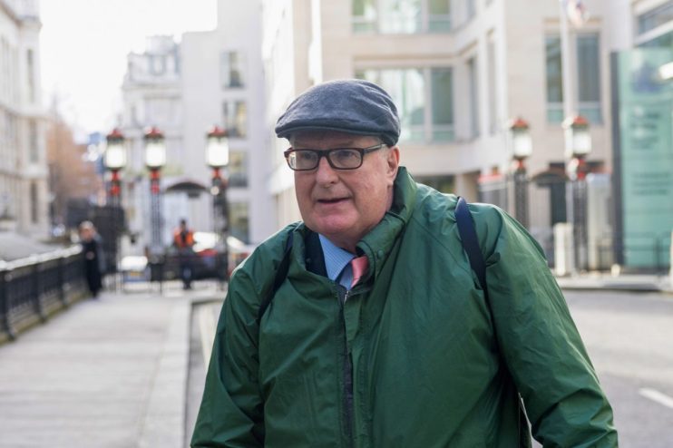 Crispin Odey standing in a formal suit at a business event, engaging in conversation with attendees, showcasing business n...