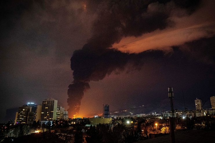 Damaged oil facility in Iran with smoke and debris following a strike, highlighting impact on energy infrastructure and re...