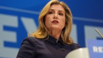 Penny Mordaunt delivering a speech at a podium, dressed in business attire, addressing a professional audience