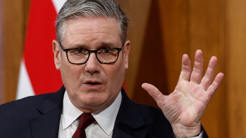 Keir Starmer stands with a British flag, highlighting political leadership and national pride in a business news context.