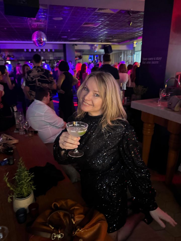 Susannah Streeter enjoying a vibrant day rave, surrounded by colorful lights and a lively crowd in a business casual setting