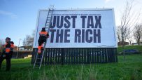 Protest sign advocating tax reforms for wealth distribution, displaying bold text Tax the Rich during a public demonstration.
