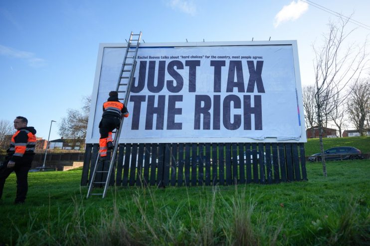 Protest sign advocating tax reforms for wealth distribution, displaying bold text Tax the Rich during a public demonstration.