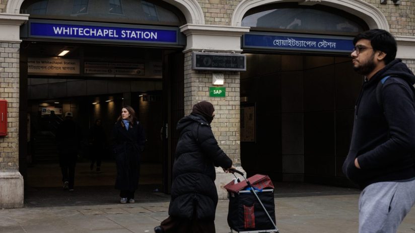 Whitechapel street scene with historic architecture, bustling market stalls, and diverse community in vibrant urban setting.