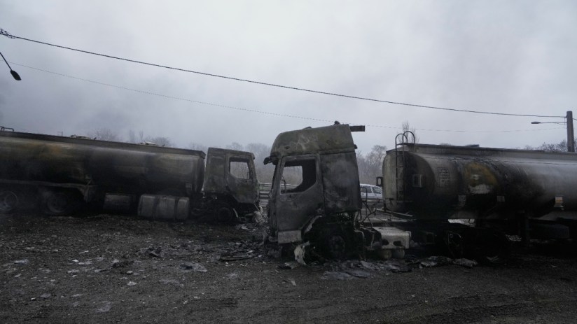 Charred oil tankers aftermath of an explosion at a refinery, with smoke billowing and emergency crews assessing the damage.