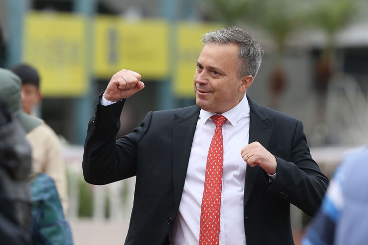 C Fownes discussing business strategies at a conference podium, surrounded by audience members attentively listening.