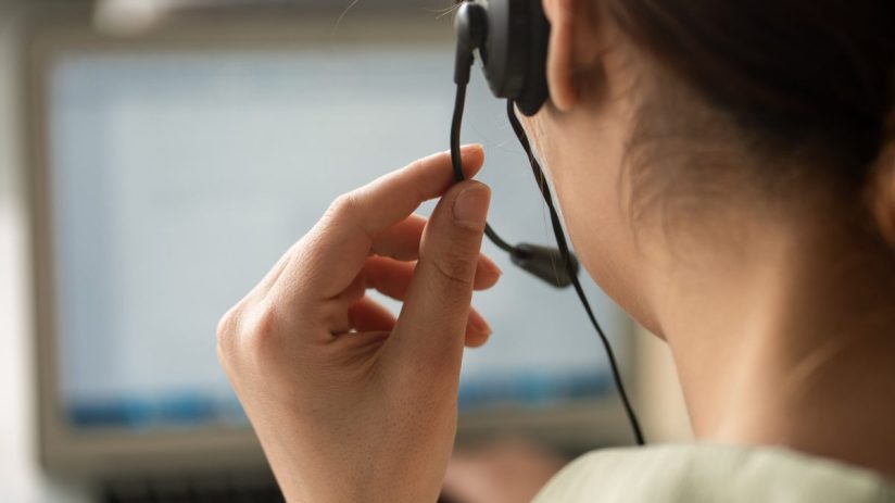 Busy call centre with diverse team of customer service representatives using headsets and computers to assist clients