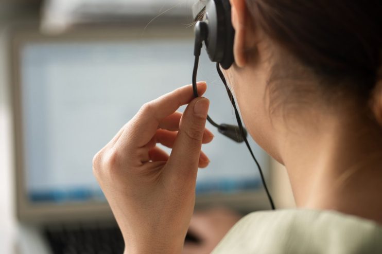 Busy call centre with diverse team of customer service representatives using headsets and computers to assist clients