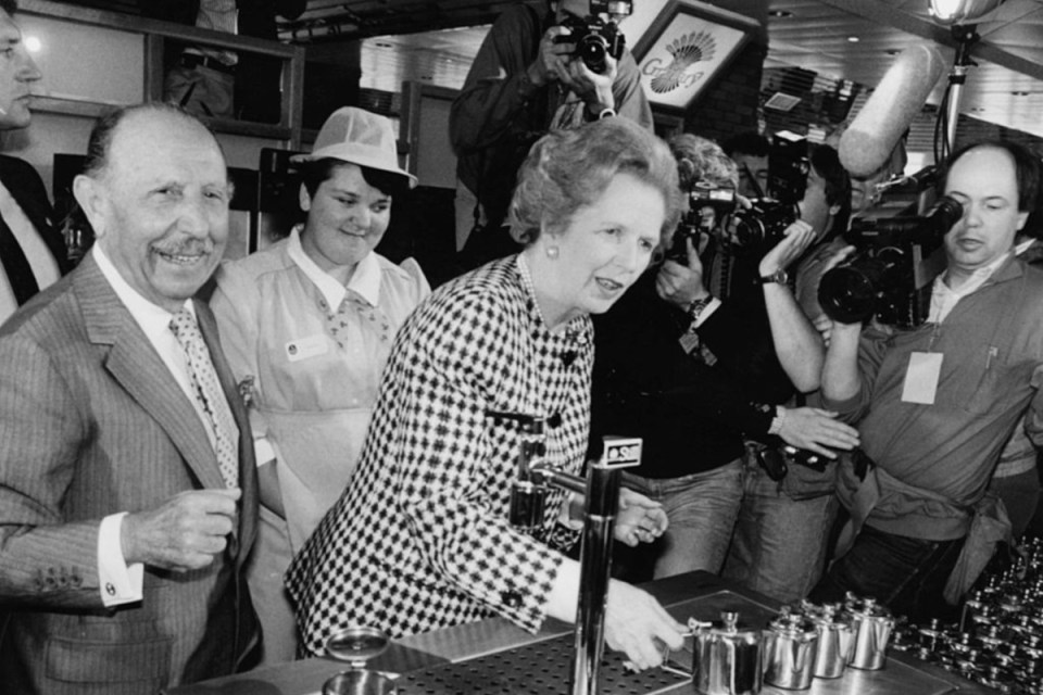 Charles Forte and Margaret Thatcher discussing business strategies at a formal meeting, both seated at a conference table.