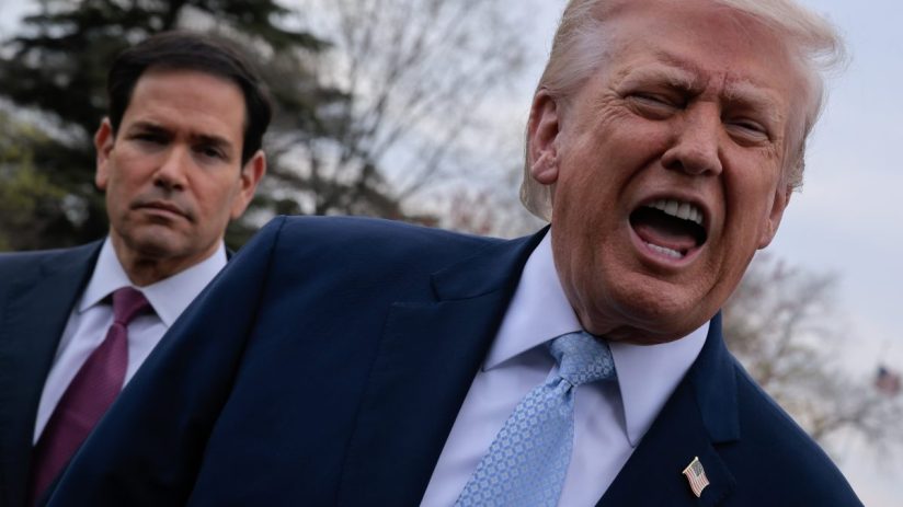 Donald Trump and Marco Rubio in conversation at a political event, both dressed in formal suits, engaging with the audience