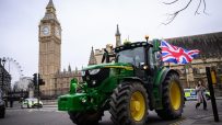 Farmers gathered in protest holding banners and signs, advocating for agricultural rights and policy reforms in rural sett...
