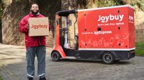 JoyExpress delivery van transporting packages amidst spring blossoms, promoting JoyBuys 2026 seasonal shipping service.