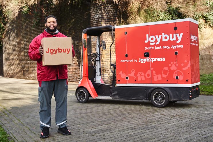 JoyExpress delivery van transporting packages amidst spring blossoms, promoting JoyBuys 2026 seasonal shipping service.