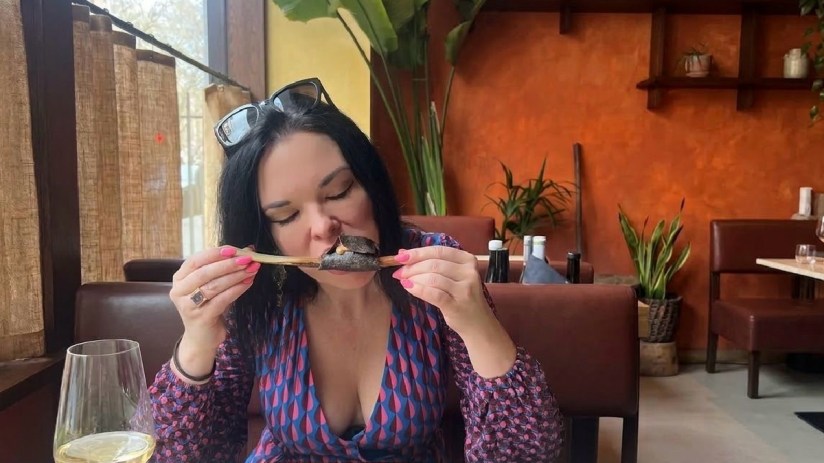 Libby Curry speaking at a news conference podium wearing a formal suit, addressing media reporters with microphones.
